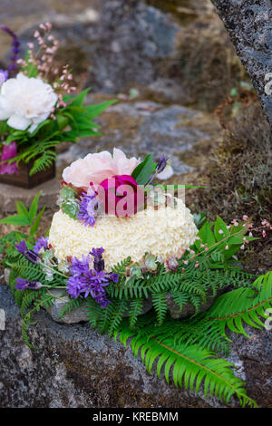 Wedding cake on river rock with native species plants and flowers at a North Umpqua River elopement wedding in Oregon. Stock Photo