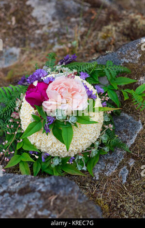 Wedding cake on river rock with native species plants and flowers at a North Umpqua River elopement wedding in Oregon. Stock Photo