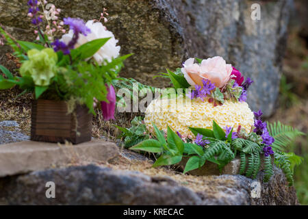 Wedding cake on river rock with native species plants and flowers at a North Umpqua River elopement wedding in Oregon. Stock Photo