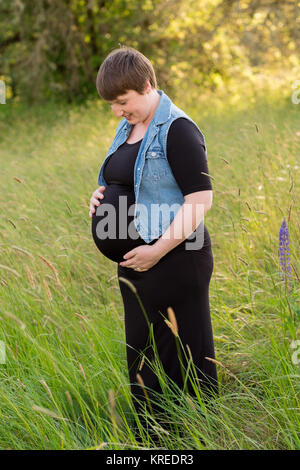 Maternity photo of a young woman with a short hair pixie cut in her third trimester with child. Stock Photo
