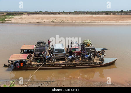 SUVs and passengers on board of ferry boat to cross Mania River. Madagascar, Africa. Stock Photo