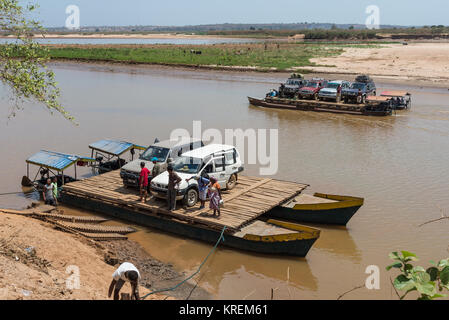 SUVs and passengers on board of ferry boat to cross Mania River. Madagascar, Africa. Stock Photo