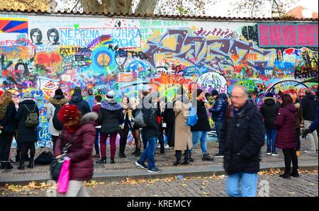 PRAGUE, CZECH REPUBLIC - DECEMBER 09, 2017: The tourist looking at memorial John Lennon Wall with graffiti paintings and pieces of lyrics from Beatles Stock Photo