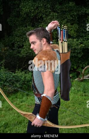 young medieval archer with chain mail reaches for arrow,with bow in hand in nature Stock Photo
