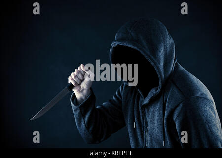 Hooded man with knife in the dark Stock Photo