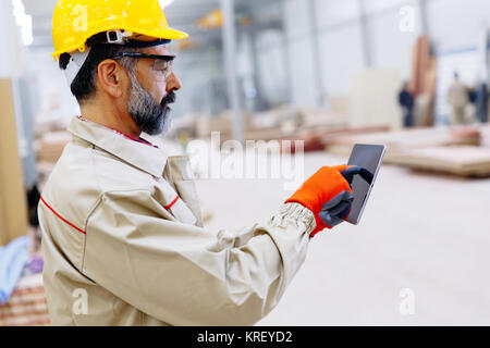 Handsome mature engineer in the factory with digital tablet Stock Photo