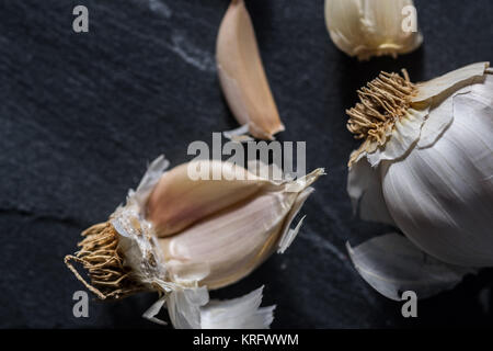 Garlic cloves closeup macro commercial studio image on dark grey or black granite stone background. Stock Photo