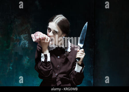 Bloody Halloween theme: crazy girl with a knife and raw meat Stock Photo