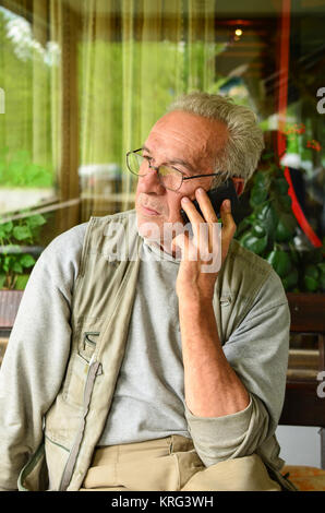 Aged man using cellphone, looking anxious after some bad news Stock Photo