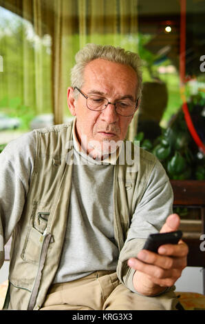 Conversation is over - aged man has just hung up, looking at the mobile phone after some bad news Stock Photo