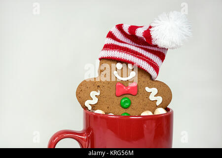 Christmas gingerbread man with stocking cap in hot chocolate drink in red mug isolated on white background Stock Photo