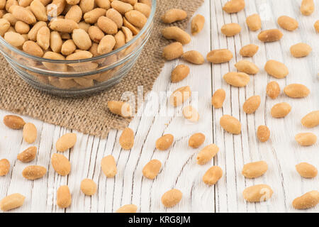 Salted peanuts in a glass bowl on the old wooden table. Stock Photo