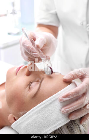 the beautician performs a needle mesotherapy treatment on a woman's face Stock Photo