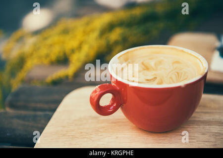 Red coffee cup in a summer day with flowers in background