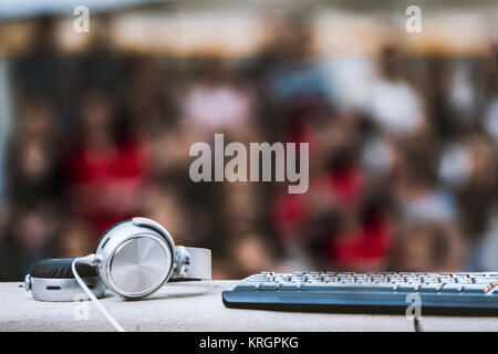 Headphones and keyboard in focus with people blurred in background - concert concept Stock Photo