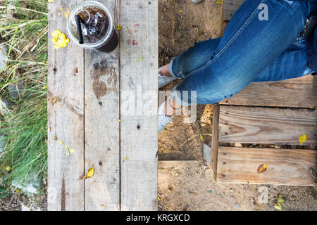 leg with jean asian girl relax time with cold drink on wooden table lifestyle in nature Stock Photo