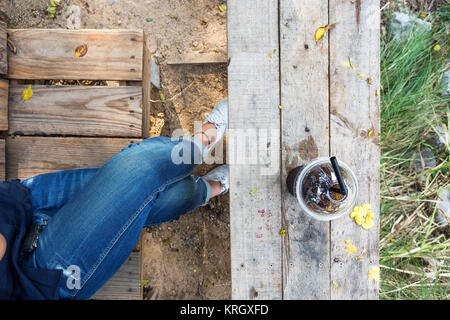 leg with jean asian girl relax time with cold drink on wooden table lifestyle in nature Stock Photo