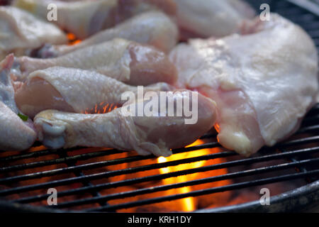 Cooking chicken drumsticks, thighs and wings on the grill. Stock Photo