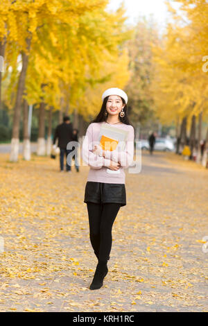 Fall girl holding the book for a walk in the path through the woods Stock Photo