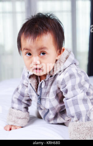 portrait of baby in jacket on a bed Stock Photo