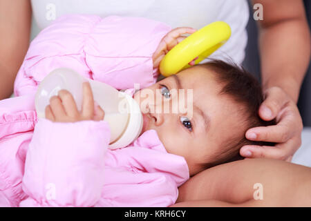 baby drinking a milk from bottle with mother on a bed Stock Photo