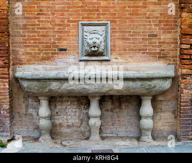 ancient source for public marble water with lion's head on brick wall ...