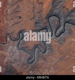The sinuous black ribbon of the San Juan River cuts deep into the sandstone-pink landscape of southeastern Utah in this Ikonos image, taken on May 9, 2004. The image shows Goosenecks State Park, where the river is surrounded by canyon walls more than 1,000 feet high. Light gray, pink, and white striations (parallel lines) on the canyon walls mark where the river has eaten away at the ancient landscape to reveal 16 layers of geology, the oldest of which is well over 300 million years old.  The ancient San Juan River flows out of the San Juan Mountains in southwestern Colorado. Early in its hist Stock Photo