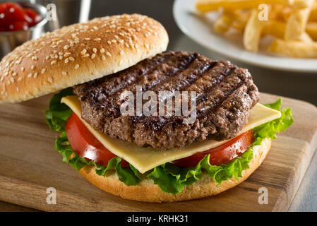 A delicious grilled Angus burger with cheese, lettuce, and tomato on a sesame seed bun. Stock Photo