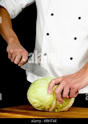 Professional chef holding a sharp cooking knife onto a whole cabbage Stock Photo