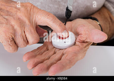 Senior Woman Pressing Alarm Button Stock Photo