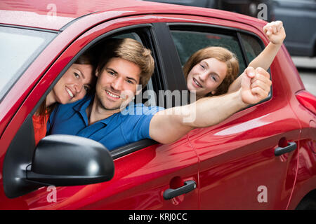 Family Sitting In Car Raising Their Arms