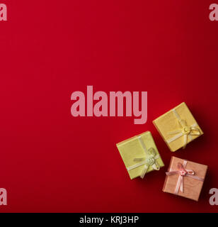 Three small gift boxes with ribbons on red background Stock Photo
