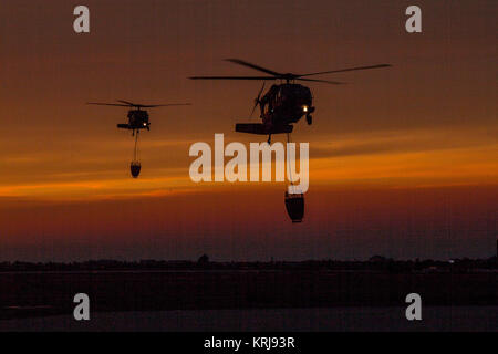 A pair of California National Guard UH-60 Black Hawk helicopters from B Company, 1st Battalion, 140th Aviation Regiment, return at sunset to Camarillo Airport in Camarillo, California, Sun., Dec. 10, 2017, after making their last water drops of the day on the Thomas Fire burning in Ventura County. (U.S. Air National Guard Stock Photo
