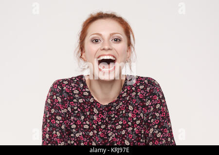 Showing teeth. Beautiful redhead woman open mouth and showing white and healthy teeth. Isolated on gray background Stock Photo