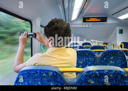 Woman Filming/Photographing from a Window While Travelling on a Train in Sydney, New South Wales (NSW), Australia Stock Photo