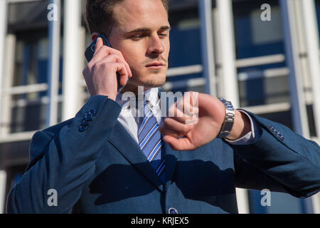 Serious businessman checking time talking on phone. Stock Photo