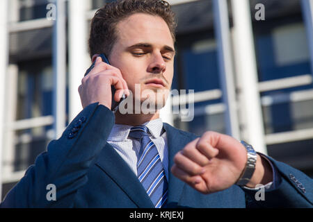 Serious businessman checking time talking on phone. Stock Photo