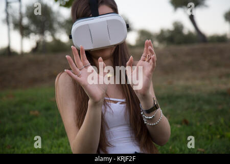 Smiling brunette having fun while using glasses of virtual reality in park. Stock Photo