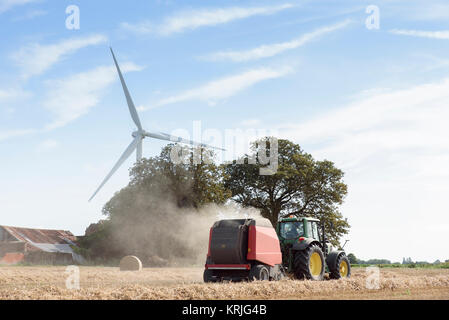 Caucasian man driving tractor near wind turbine Stock Photo