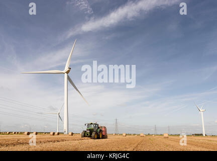 Caucasian man driving tractor near wind turbines Stock Photo