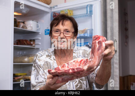 Happy senior woman with raw pork ribs Stock Photo