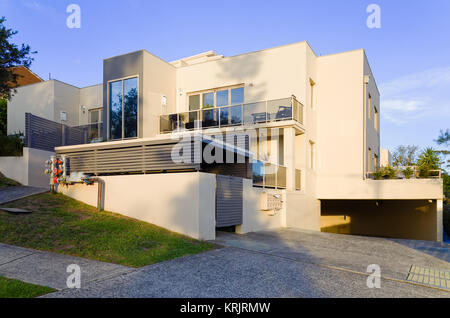 Modern residential apartment building exterior with large balcony and windows. Luxury aparment house garage and driveway on a suburban street in Brook Stock Photo