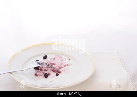 dish with leftover of a cake with bluberries and fork, on white background Stock Photo