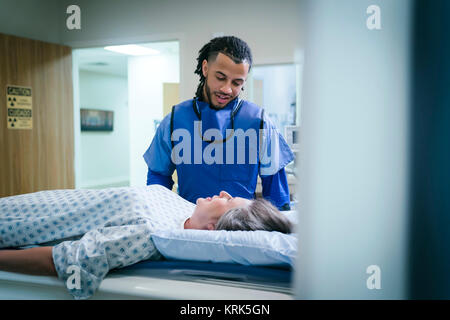 Technician talking to patient near scanner Stock Photo