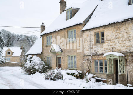 Church row cottages in Chedworth village in the december snow. Chedworth, Cotswolds, Gloucestershire, England Stock Photo