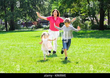 Grandmother And Grandchildren Running In Park Stock Photo