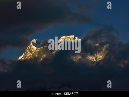 Annapurna III seen through the clouds at sunrise, with Ngawal village below, Annapurna Circuit, Nepal Stock Photo