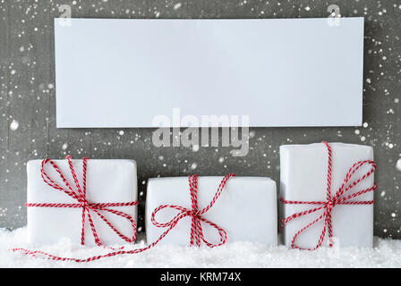 Three Christmas Gifts Or Presents On Snow. Cement Wall As Background With Snowflakes. Modern And Urban Style. Card For Birthday Or Seasons Greetings. Label With Copy Space For Advertisement Stock Photo