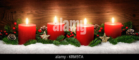 advent decoration with four candle flames,snow,pine branches and wood background Stock Photo