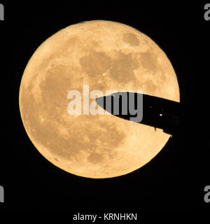 An aircraft taking off from Ronald Reagan National Airport is seen passing in front of the Moon as it rises, Sunday, Dec. 3, 2017 in Washington.  Today's full Moon is the first of three consecutive supermoons. The two will occur on Jan. 1 and Jan. 31, 2018. A supermoon occurs when the moon’s orbit is closest (perigee) to Earth at the same time it is full. Photo Credit: (NASA/Bill Ingalls) Supermoon in Washington, D.C. (NHQ201712030003) Stock Photo